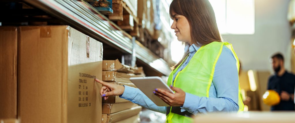 Woman inspecting factory shelves for supplier approval program.