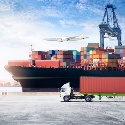 large container ship vessel with a plane overhead and a large truck at a port.