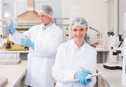 A woman wearing Personal Protective Equipment (PPE) and smiling in a food safety testing lab.
