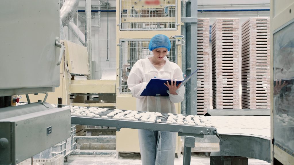 Woman looking at a binder and inspecting for validation and verification of a food safety and quality program.